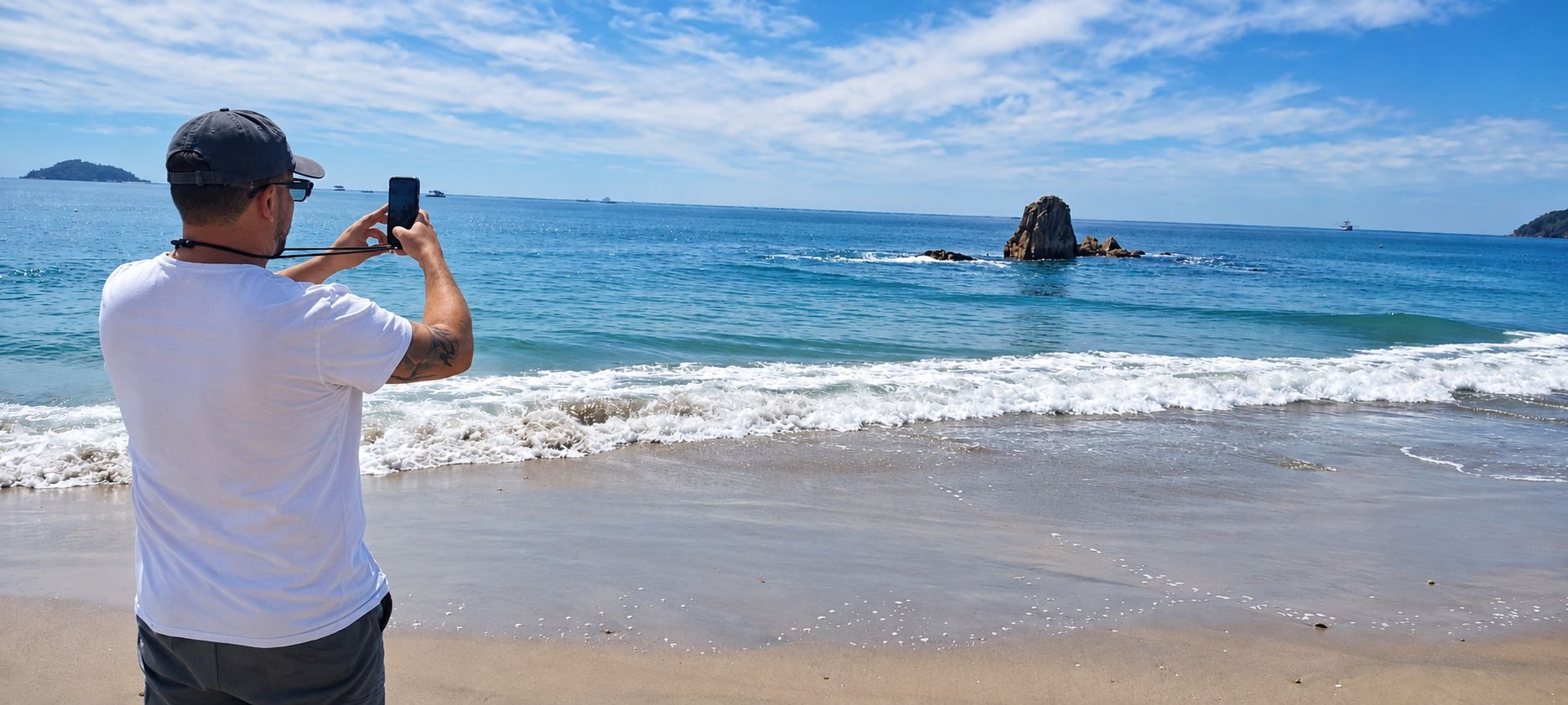 Enrique na praia, filmando as ondas com o celular